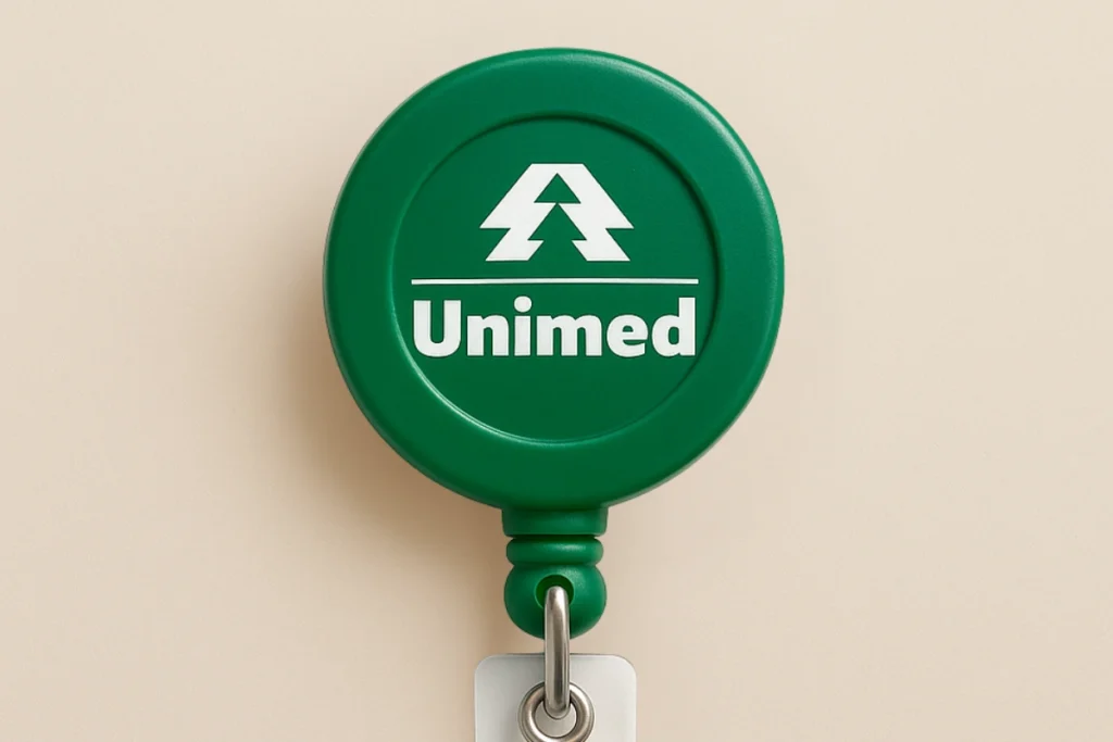 Roller clip verde personalizado com logotipo branco da Unimed, usado para crachás em ambientes corporativos e hospitalares