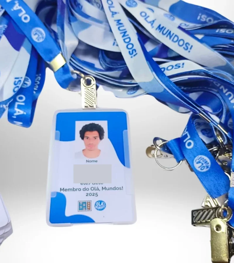 Crachás personalizados com cordão azul estampado da organização Olá, Mundos! 2025, incluindo foto e identificação dos participantes.